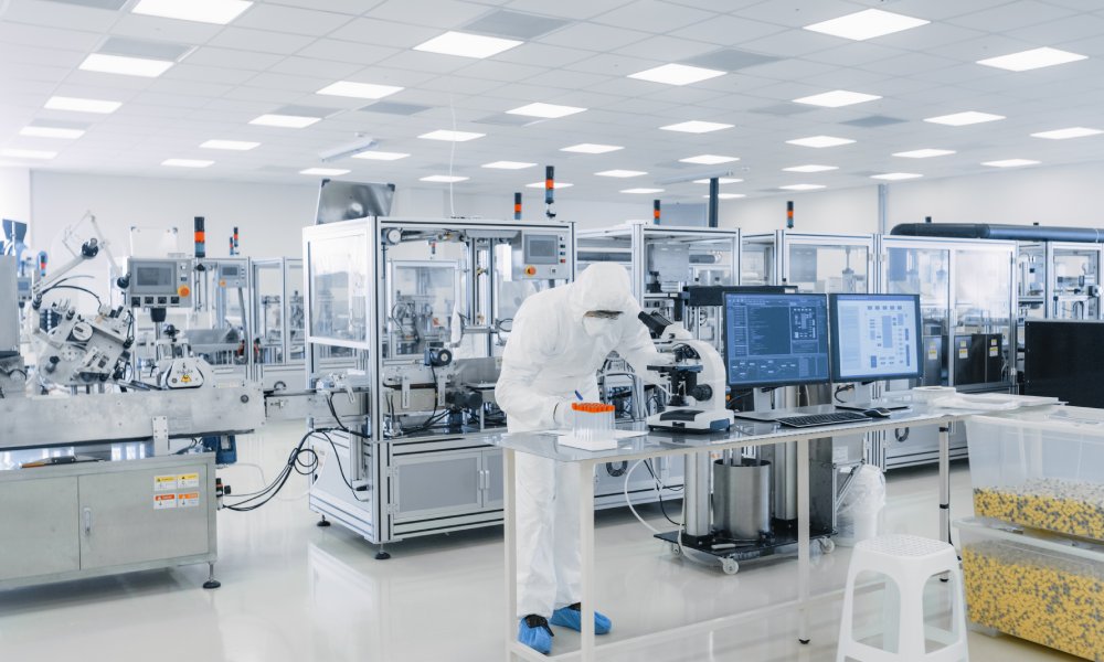 A technician uses machinery to complete a task during the pharmaceutical manufacturing process.