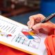 A safety engineer using a pen to make a mark on a health risk assessment sheet on a page with chemical symbols.